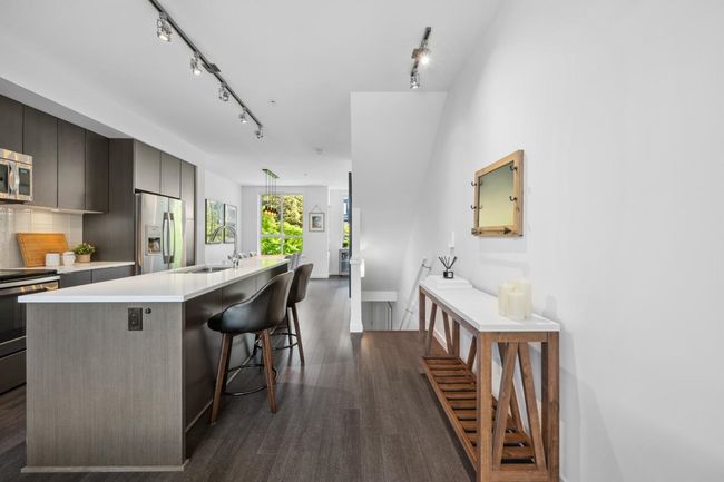 Kitchen featuring appliances with stainless steel finishes, a sink, rail lighting, and dark wood-style floors | Image 9