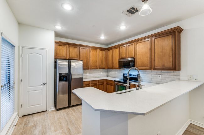 This beautifully updated kitchen combines functionality with sleek, modern design. Quartz countertops provide a durable and elegant workspace, complemented by a striking modern backsplash that adds visual interest and a touch of sophistication. | Image 10