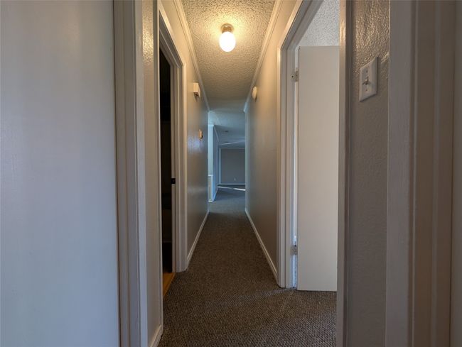 Hallway with dark carpet and a textured ceiling | Image 16