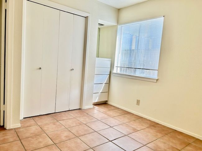 Unfurnished bedroom with light tile patterned floors, baseboards, and a closet | Image 10