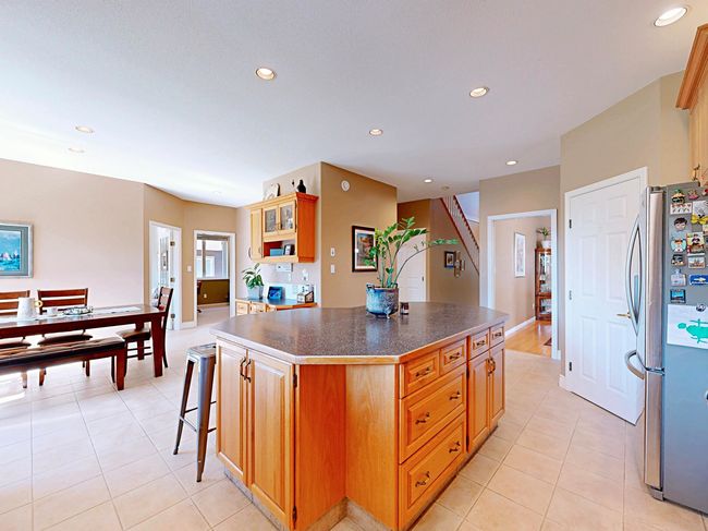 Kitchen with freestanding refrigerator, a center island, light tile patterned floors, recessed lighting, and dark countertops | Image 4