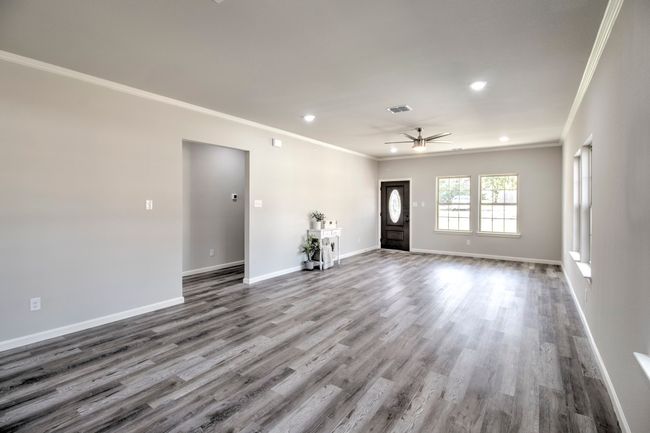 Unfurnished living room with ornamental molding, a ceiling fan, wood finished floors, and recessed lighting | Image 4