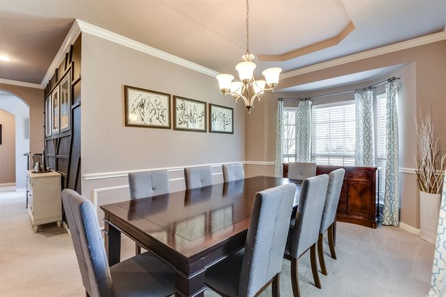 Carpeted dining space with a tray ceiling, crown molding, and a notable chandelier | Image 8