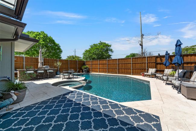 View of swimming pool featuring a patio area, a pool with connected hot tub, an outdoor living space, and a fenced backyard | Image 33