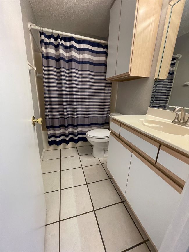 Bathroom with vanity, tile patterned flooring, a textured ceiling, and a shower with shower curtain | Image 9