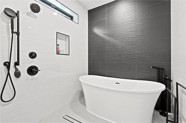 Full bath with tile walls, a soaking tub, and a tile shower | Image 21