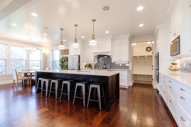Kitchen with stainless steel appliances, a chandelier, light countertops, a kitchen breakfast bar, and backsplash | Image 8