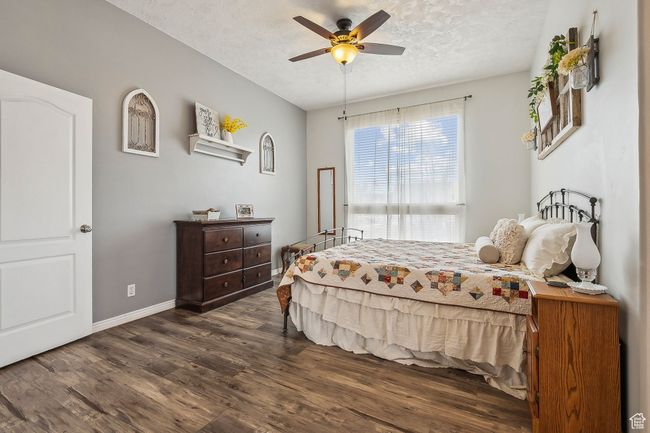 Bedroom featuring ceiling fan, baseboards, a textured ceiling, and dark wood-style floors | Image 21