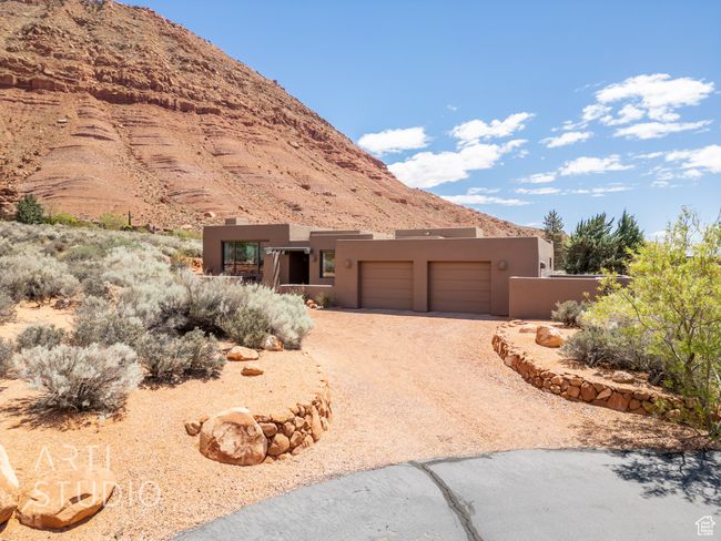 View of front of property featuring a mountain view, stucco siding, an attached garage, and dirt driveway | Image 42