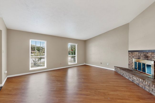 Unfurnished living room with wood finished floors and a brick fireplace | Image 4