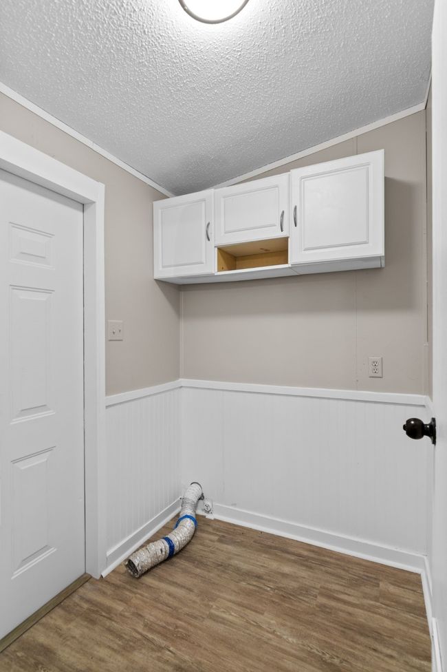 Laundry room featuring a textured ceiling, wood finished floors, wainscoting, and ornamental molding | Image 21