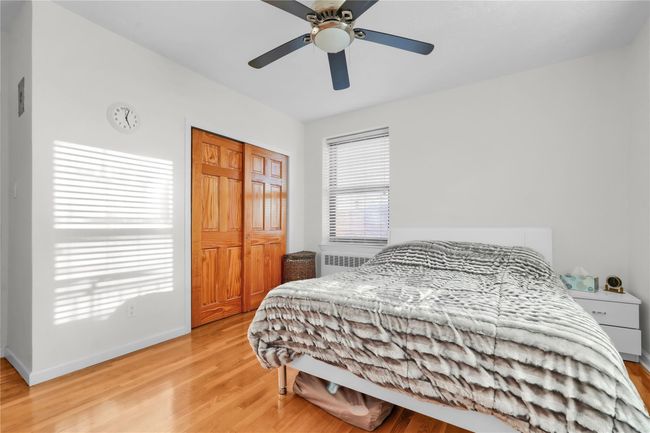 Bedroom with light wood-type flooring, radiator, and ceiling fan | Image 6