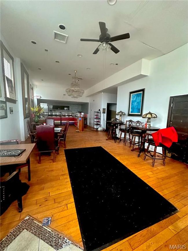 Living room with visible vents, hardwood / wood-style floors, and ceiling fan with notable chandelier | Image 7
