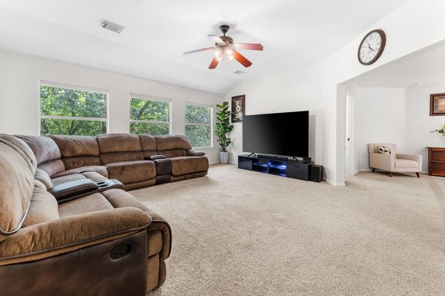 Carpeted living room featuring a ceiling fan, lofted ceiling, and baseboards | Image 29