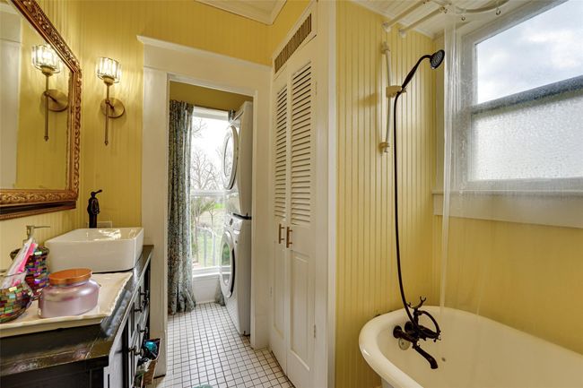 Full bathroom with stacked washer / drying machine, tile patterned floors, vanity, and a freestanding bath | Image 19