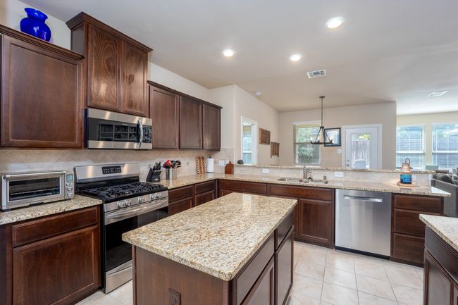 Kitchen featuring stainless steel appliances, light stone counters, recessed lighting, dark brown cabinets, and backsplash | Image 6