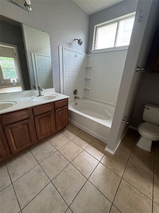 Bathroom with plenty of natural light, double vanity, tile patterned flooring, toilet, and a textured wall | Image 17