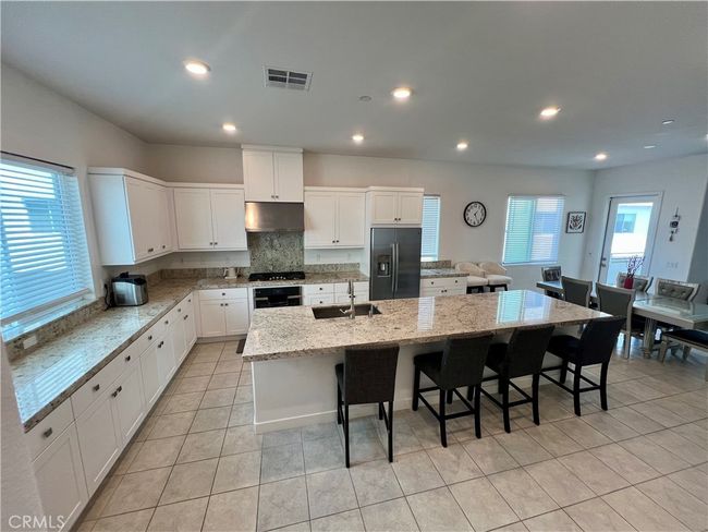 Modern kitchen with large granite island and lots of cabinets and storage. | Image 4