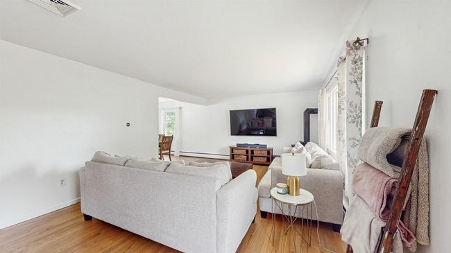 Nice sized Living room featuring baseboard heating, finished light wooden floors and a gas stove. | Image 7
