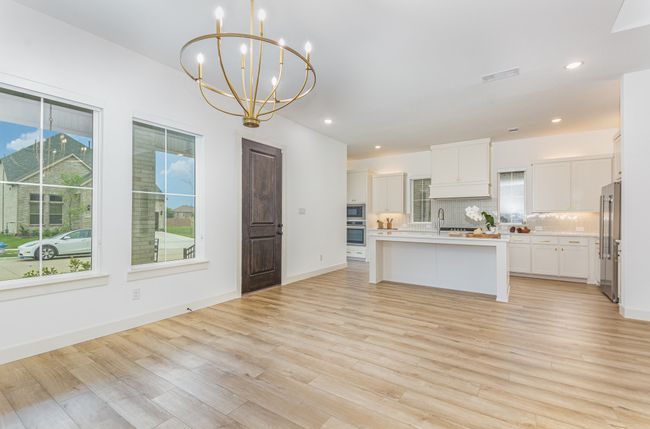 Kitchen with high quality fridge, a chandelier, plenty of natural light, light countertops, and recessed lighting | Image 9