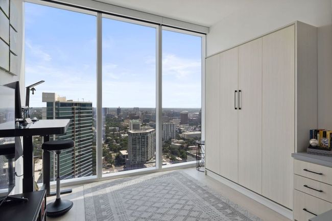 Unfurnished bedroom featuring multiple windows and a view of city | Image 25