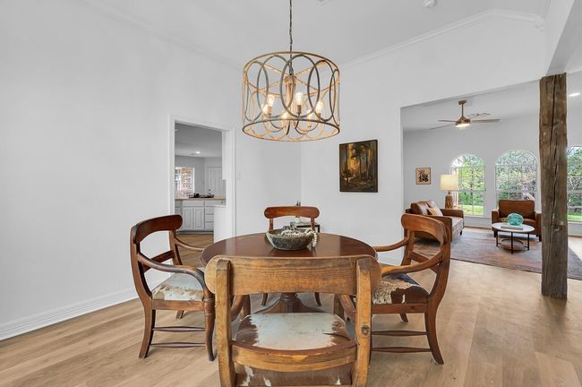 Dining area open to living area, with notable chandelier, light wood-style flooring, baseboards, and ornamental molding | Image 19