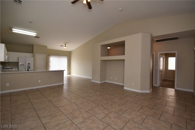 Unfurnished living room featuring vaulted ceiling, visible vents, ceiling fan, and light tile patterned flooring | Image 4