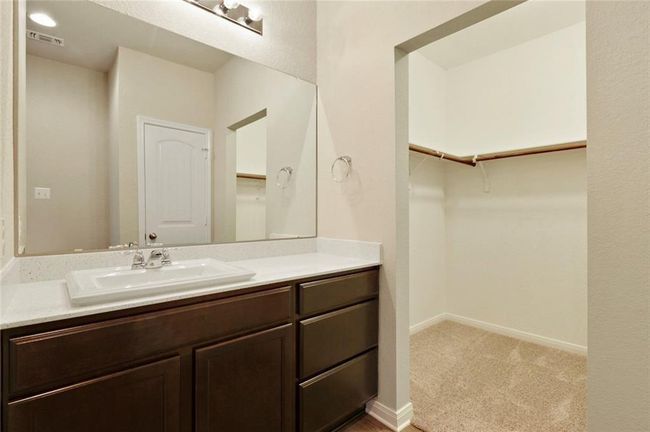 Bathroom featuring vanity, a walk in closet, and baseboards | Image 14