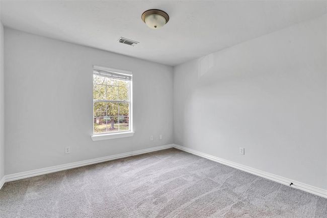 This room features neutral walls and carpet, a ceiling light fixture, and a window providing natural light and a view of the outdoors. Ideal for a bedroom or office space. | Image 32