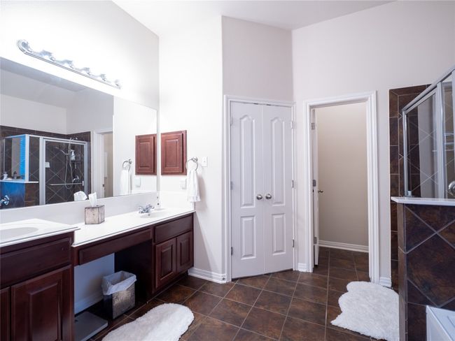Primary bathroom featuring double vanity, a stall shower, soaking tub and tile flooring. | Image 15