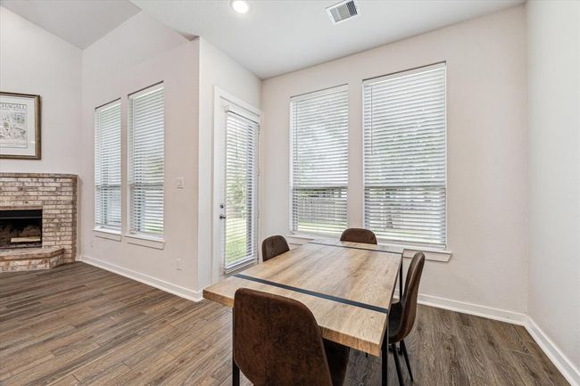 This informal dining area is open to the living area and surrounded by tall windows. | Image 6