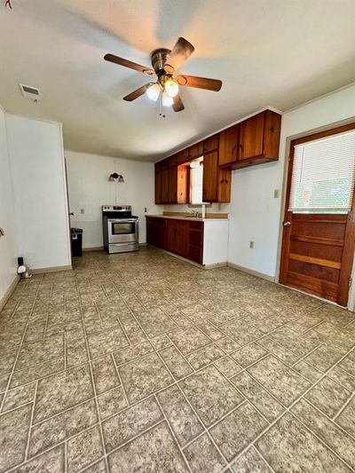 Kitchen with stainless steel range with electric stovetop, ceiling fan, and light tile patterned floors | Image 2