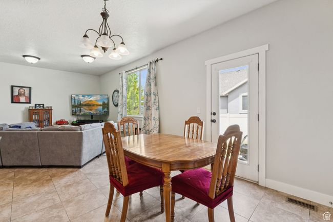 Dining area with a chandelier and light tile patterned floors | Image 8