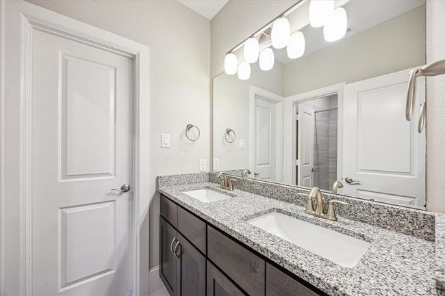 This second floor bathroom features a double vanity with granite countertops, sleek under-mount sinks, and modern fixtures. It has ample storage space and is well-lit with stylish overhead lighting. | Image 29