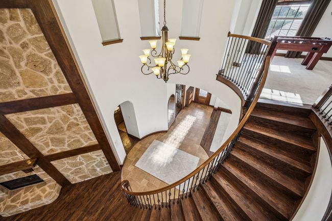 Staircase with arched walkways, wood finished floors, a chandelier, and a towering ceiling | Image 16