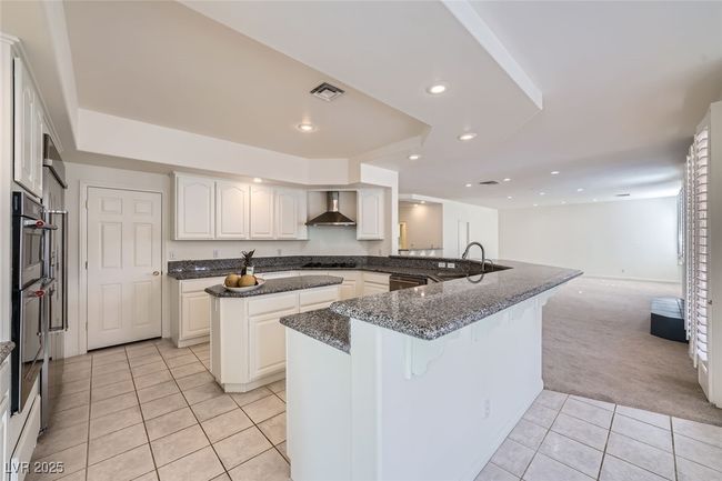 Kitchen with visible vents, dishwasher, wall chimney exhaust hood, black stovetop, and a sink | Image 25