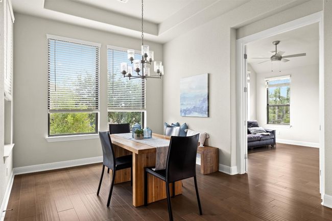 Dining space featuring a chandelier, dark wood-type flooring, a ceiling fan, and a tray ceiling | Image 20