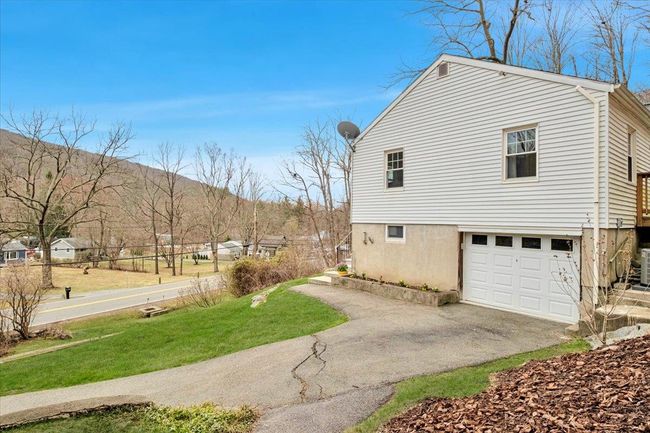 View of property exterior with a lawn, aphalt driveway, a garage, and cooling unit | Image 21