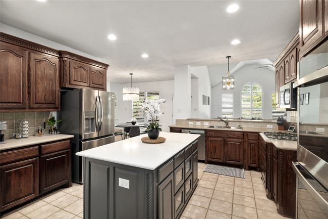 Kitchen with a chandelier, light tile patterned floors, backsplash, appliances with stainless steel finishes, and a sink | Image 13