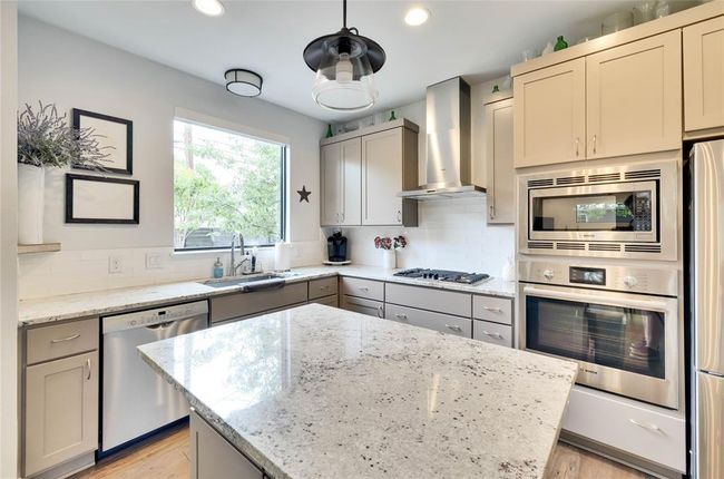 Kitchen with appliances with stainless steel finishes, wall chimney range hood, gray cabinetry, decorative backsplash, and recessed lighting | Image 6