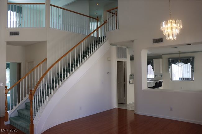 Staircase with a high ceiling, a chandelier, wood finished floors, and arched walkways | Image 21