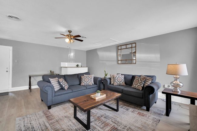 Living room with attic access, baseboards, visible vents, a ceiling fan, and wood finished floors | Image 12