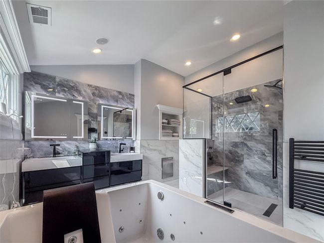 Bathroom with a stall shower, double vanity, a jetted tub, lofted ceiling, and a towel warmer | Image 21