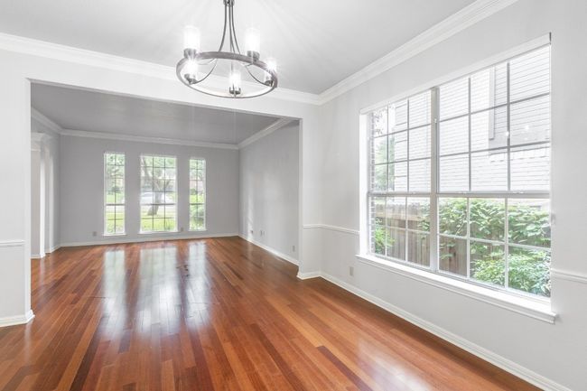 Empty room featuring a chandelier, wood finished floors, baseboards, and crown molding | Image 22