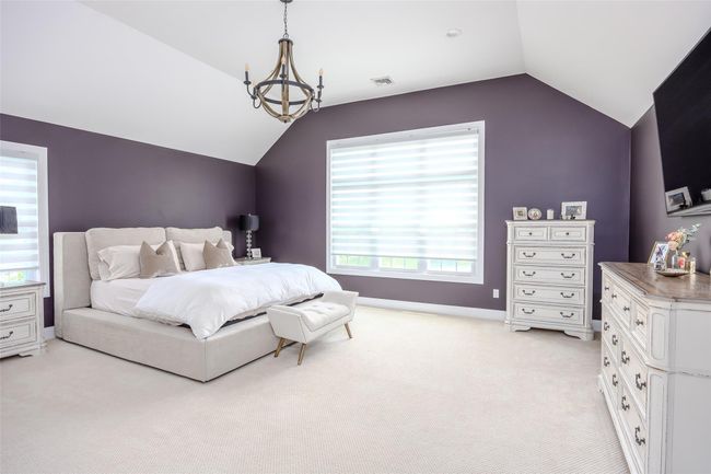 Bedroom with lofted ceiling, light colored carpet, multiple windows, and a chandelier | Image 22