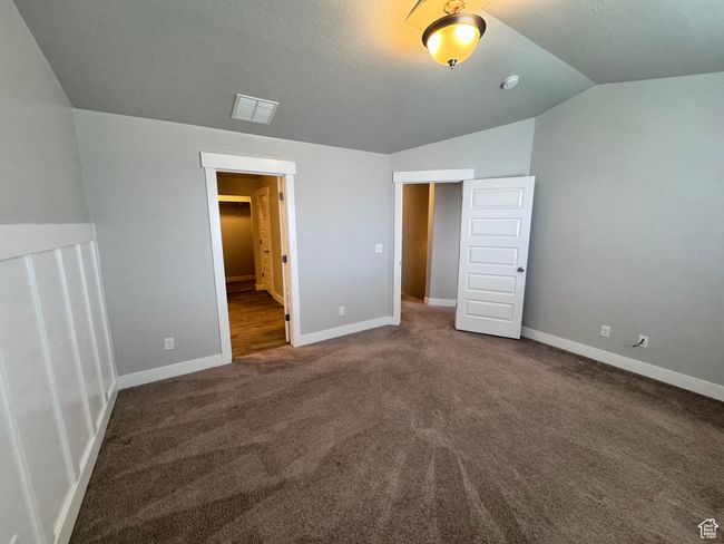 Unfurnished bedroom featuring lofted ceiling, carpet, visible vents, and baseboards | Image 12