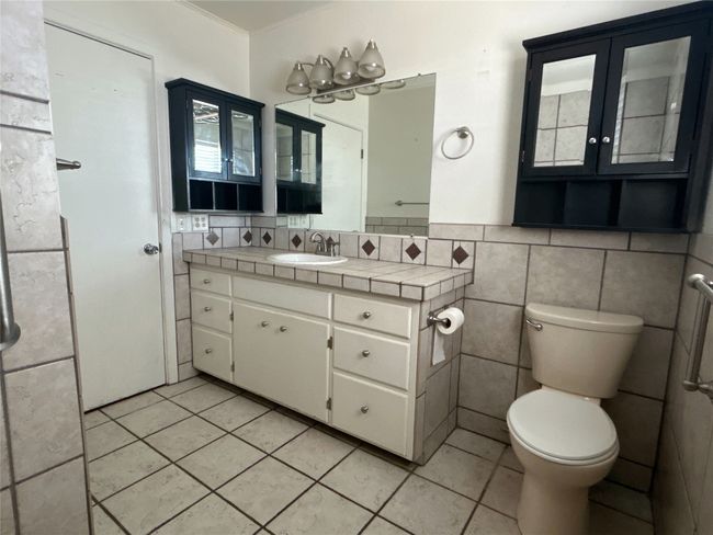 Bathroom featuring tile walls, vanity, tile patterned flooring, toilet, and wainscoting | Image 5