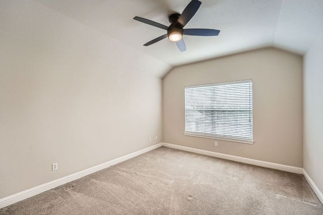 Carpeted empty room featuring baseboards, ceiling fan, and vaulted ceiling | Image 29