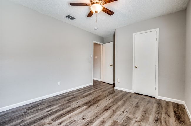 Unfurnished bedroom with wood finished floors, baseboards, a textured ceiling, and a ceiling fan | Image 15