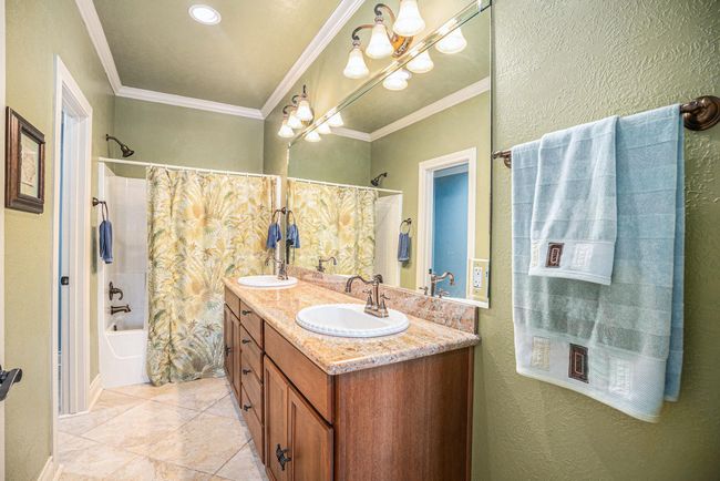 The primary ensuite bathroom is well-appointed, featuring a dual-sink vanity, a walk-in closet, and elegant crown molding. | Image 18